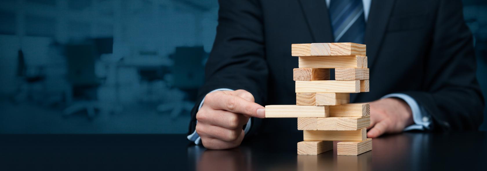 Man wearing a suit playing the wooden block game Jenga