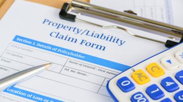Property/Liability Claim Form on a clipboard with a pen and calculator