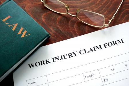 Work Injury claim form, law book, and pair of glasses